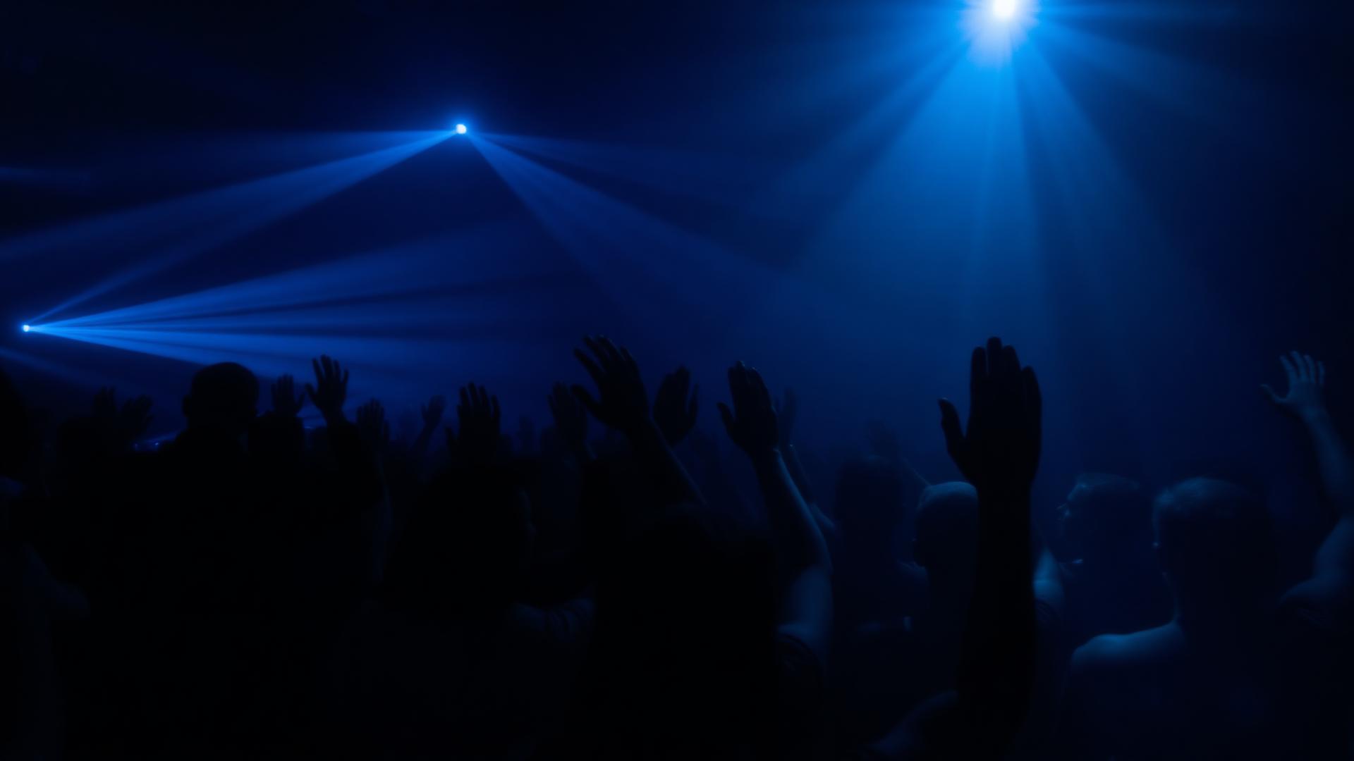 Crowd with hands in the air under blue lighting at a Charlotte event